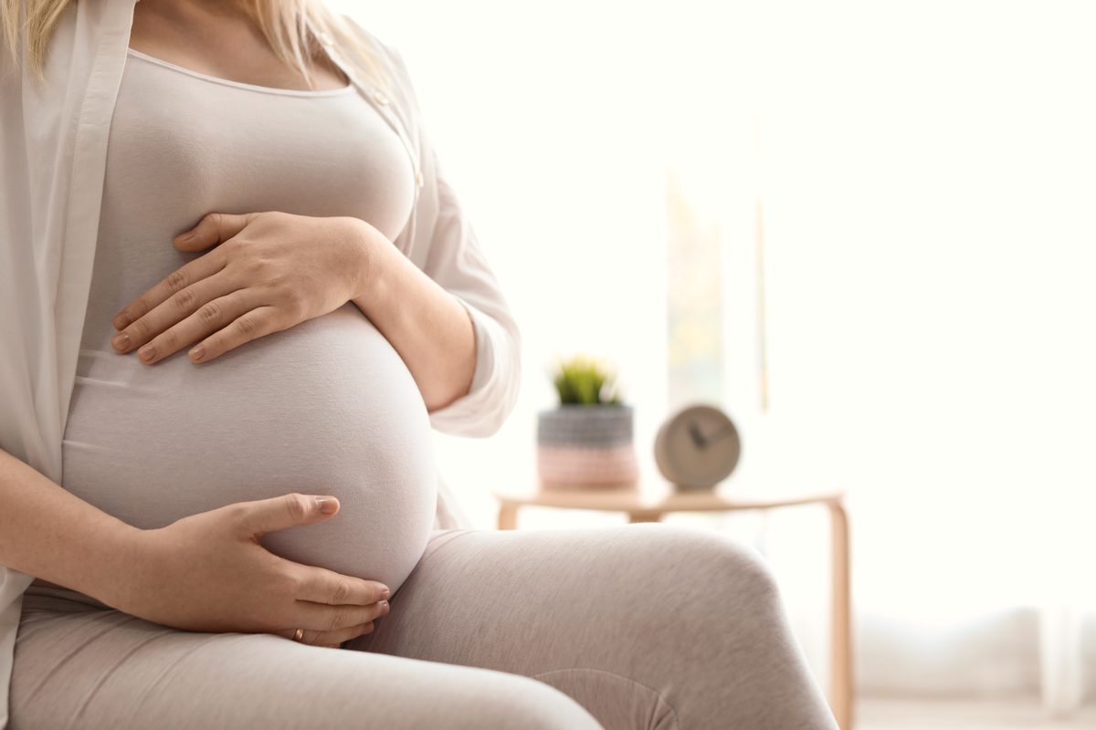 Kobieta w ciąży trzymająca dłonie na brzuchu